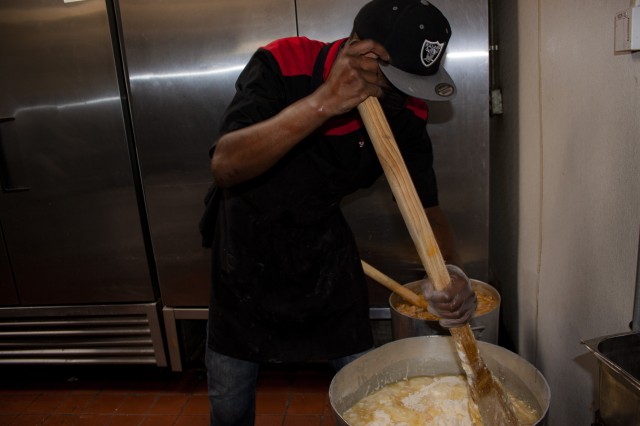 Man holding large paddle and mixing ingreadients