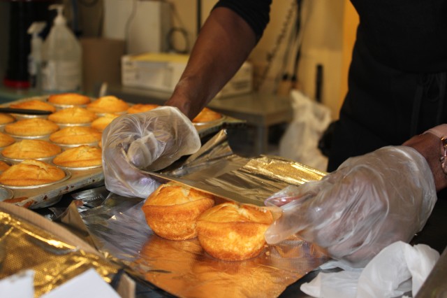 Person wrapping two cornbread muffins in foil 