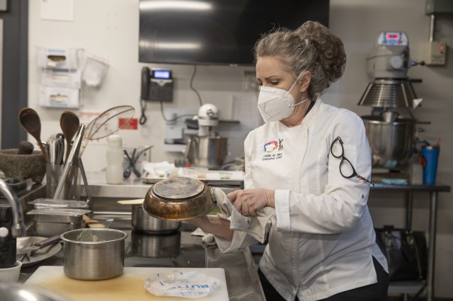 Woman in kitchen flipping over a pan 