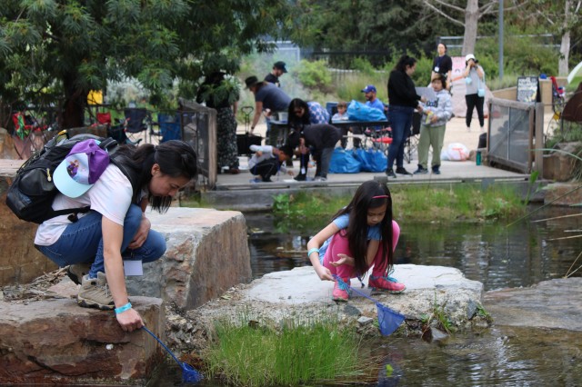 woman and child look into a pond