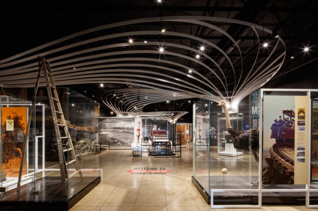 View showing the whole gallery of the Becoming Los Angeles exhibition with glass cases filled with historic objects