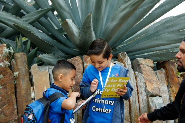 Two grade-school age students writing while in nature