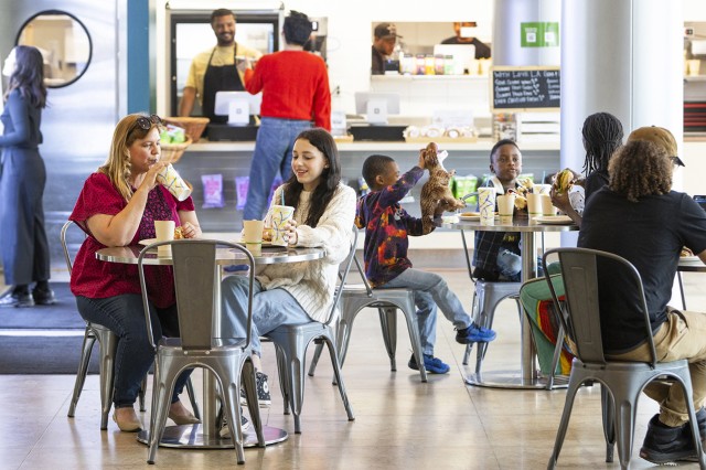 Visitors eating at tables with customers at the counter and snack shelves in the background