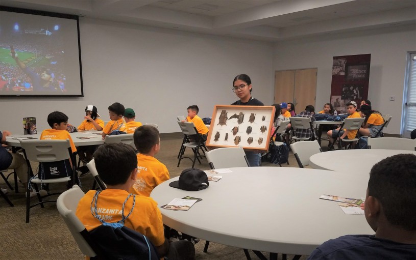 Maya holds a box with examples of local bats so elementary students can see them.