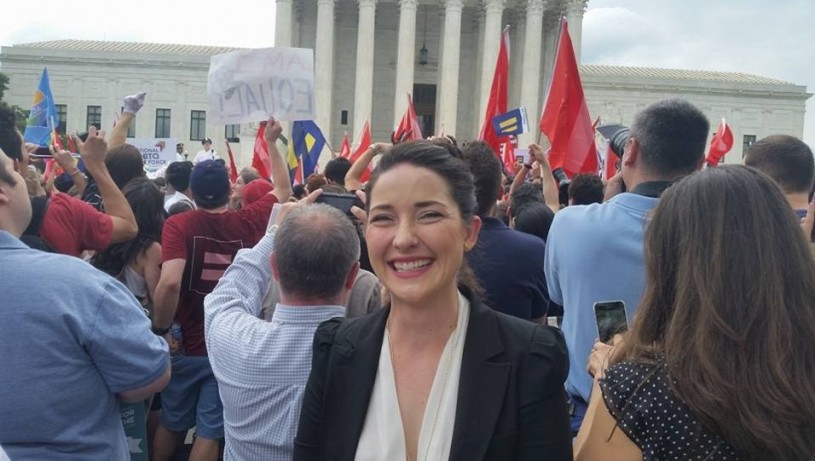 Woman standing in front of building with crowd behind her 