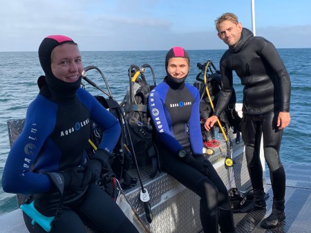 Three divers on boat in August as they prepare to dive for marine specimens.