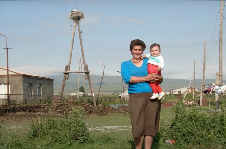 A woman and child posing in front of a tall nesting platform 